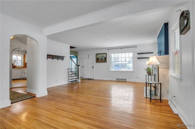 unfurnished living room with ornamental molding and hardwood / wood-style floors