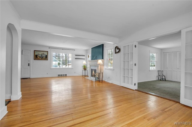 unfurnished living room featuring light wood-type flooring, plenty of natural light, and a wall mounted air conditioner