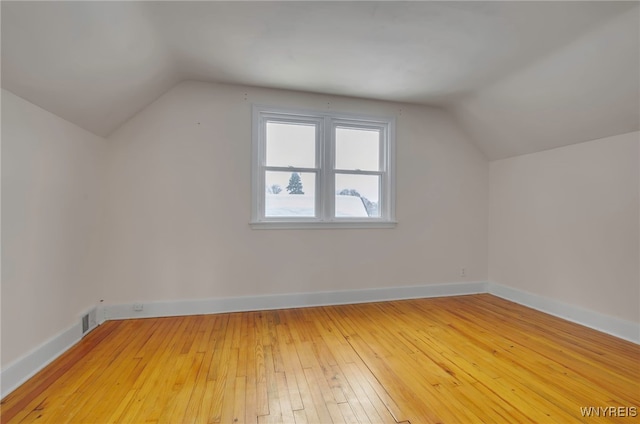 additional living space featuring lofted ceiling and hardwood / wood-style floors