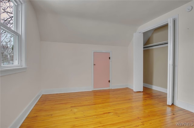 unfurnished bedroom with lofted ceiling, light wood-type flooring, and a closet