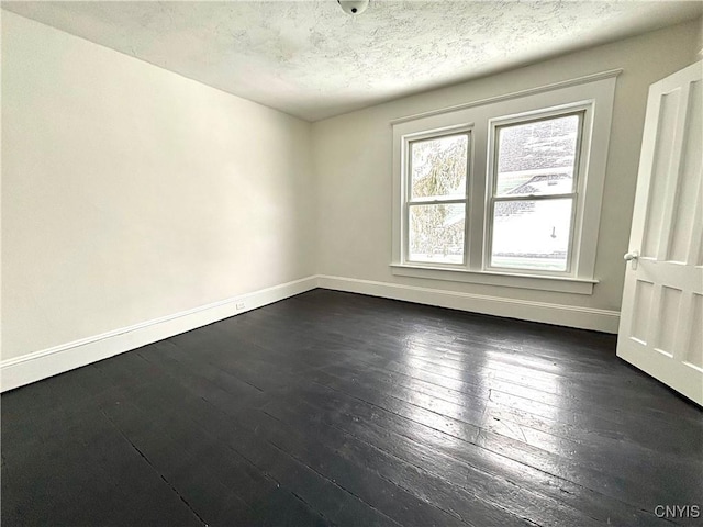 spare room featuring dark wood-type flooring and a textured ceiling