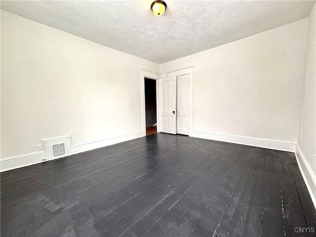 unfurnished room with a textured ceiling and dark hardwood / wood-style flooring