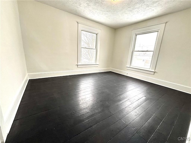 empty room featuring dark hardwood / wood-style floors and a textured ceiling