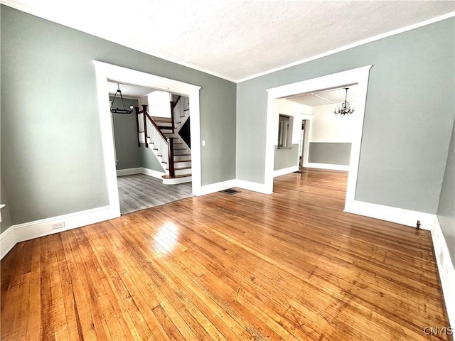 empty room featuring a textured ceiling, an inviting chandelier, and hardwood / wood-style flooring