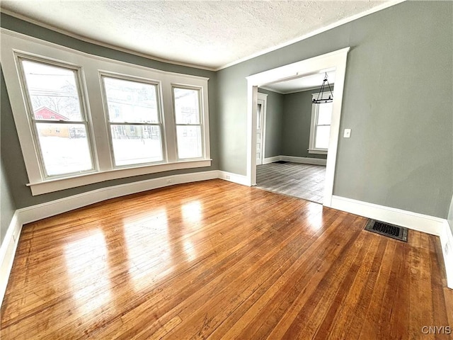 empty room with a healthy amount of sunlight, a chandelier, and hardwood / wood-style flooring