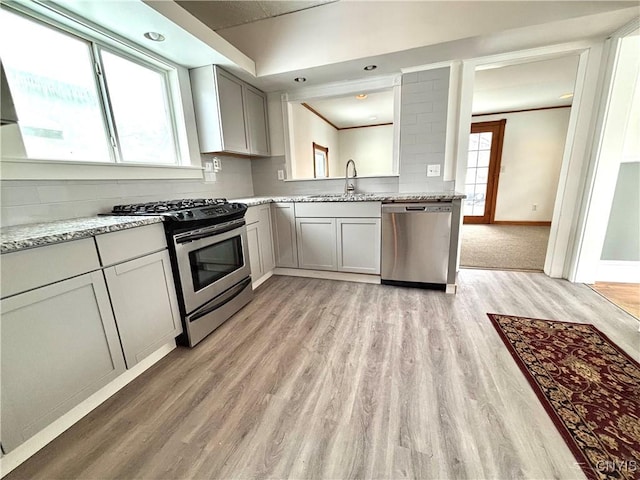 kitchen featuring light stone counters, sink, backsplash, and appliances with stainless steel finishes