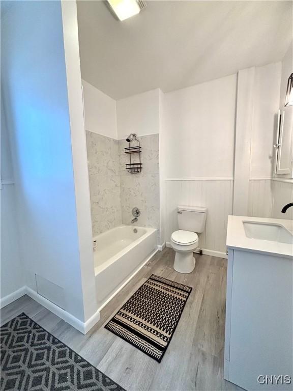 full bathroom featuring toilet, tiled shower / bath, wood-type flooring, and vanity