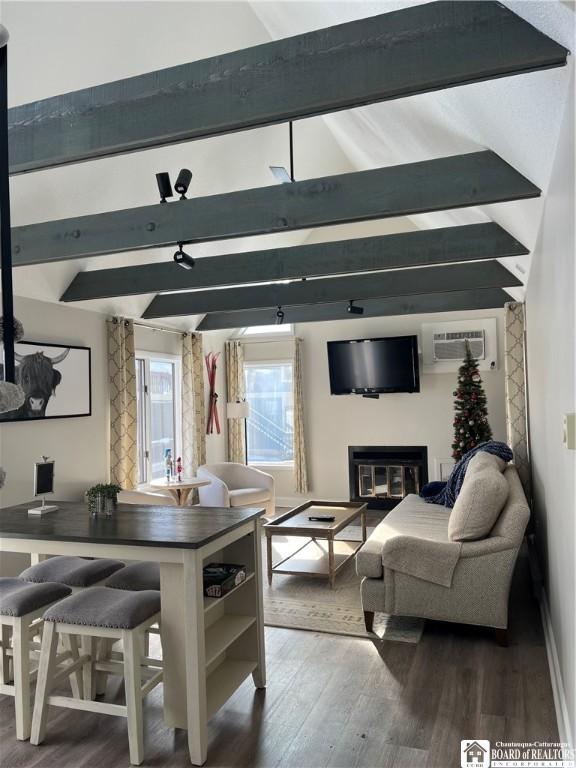 living room featuring wood-type flooring, a wall mounted AC, and vaulted ceiling with beams