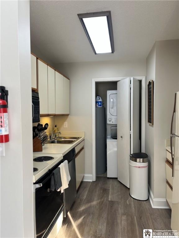 kitchen featuring white cabinetry, stacked washer / drying machine, white range with electric stovetop, dark hardwood / wood-style flooring, and sink