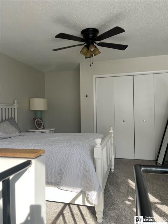 carpeted bedroom with a textured ceiling, ceiling fan, and a closet