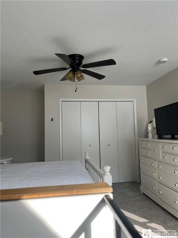 bedroom with a textured ceiling, ceiling fan, a closet, and carpet floors