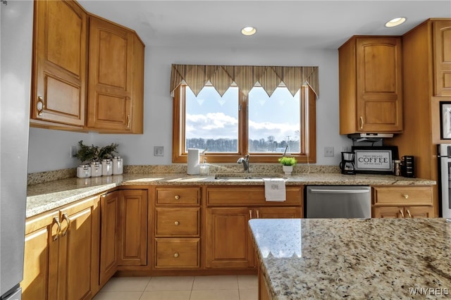 kitchen with light tile patterned floors, appliances with stainless steel finishes, light stone counters, and sink