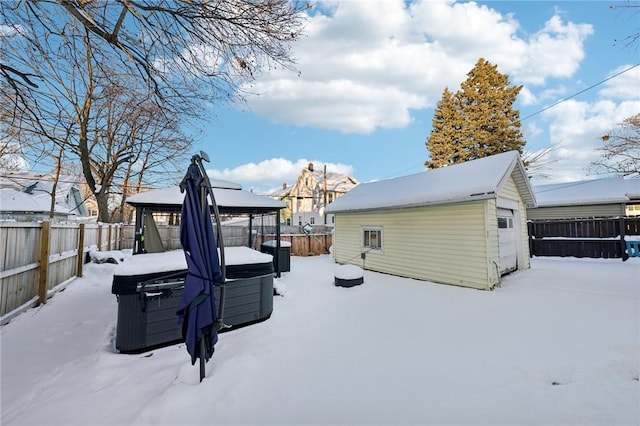 snow covered rear of property with a gazebo, a hot tub, and an outbuilding