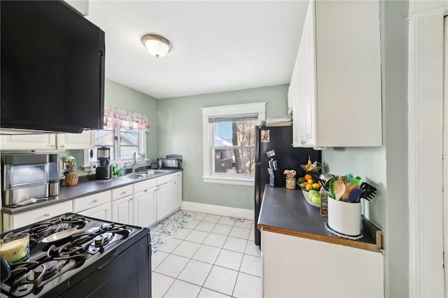 kitchen with sink, white cabinets, black appliances, and light tile patterned flooring