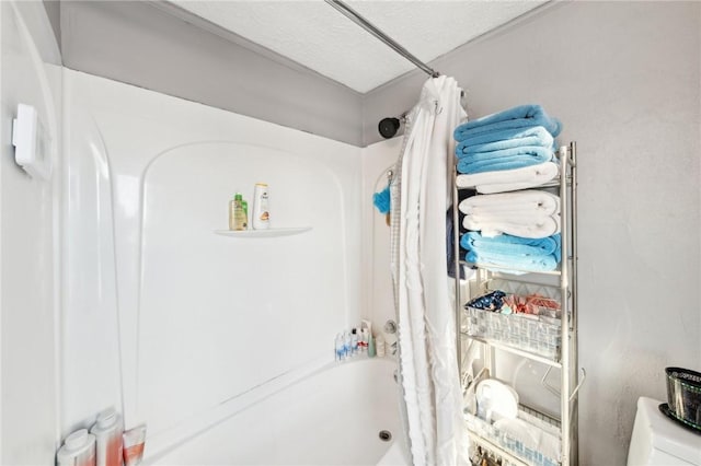 bathroom featuring a textured ceiling, toilet, and shower / bathtub combination with curtain