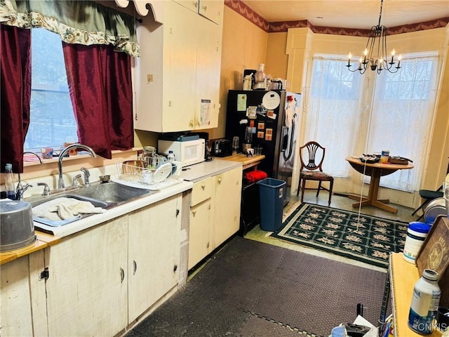 kitchen featuring sink, pendant lighting, stainless steel fridge, and an inviting chandelier