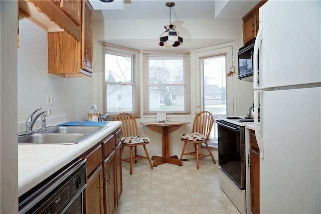 kitchen featuring decorative light fixtures, sink, and white appliances