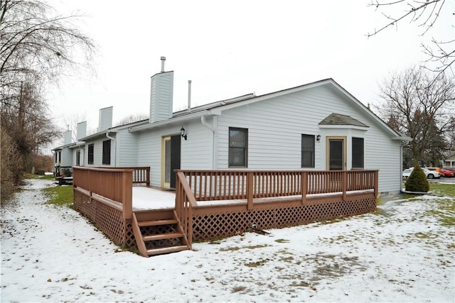 snow covered back of property featuring a wooden deck