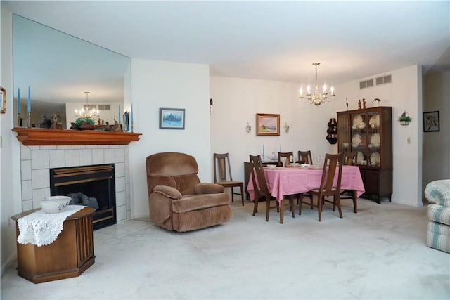 dining room featuring carpet floors, a tile fireplace, and a chandelier