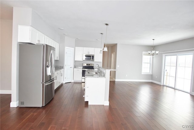 kitchen featuring white cabinets, appliances with stainless steel finishes, decorative light fixtures, an island with sink, and sink