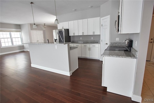 kitchen with a center island, white cabinetry, hanging light fixtures, appliances with stainless steel finishes, and light stone counters