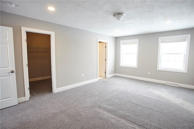 unfurnished bedroom featuring a spacious closet, a closet, and carpet flooring