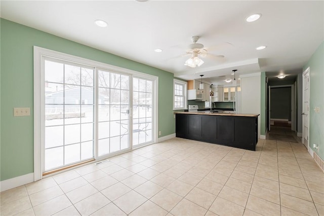 kitchen featuring ceiling fan, hanging light fixtures, light tile patterned floors, and kitchen peninsula