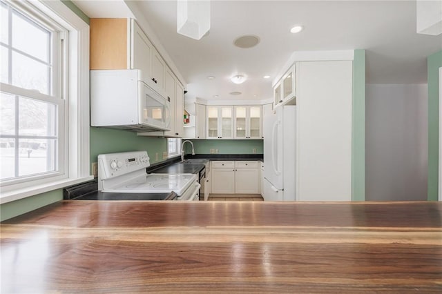 kitchen with white cabinetry, sink, and white appliances