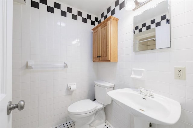 bathroom with tile patterned floors, tasteful backsplash, sink, tile walls, and toilet