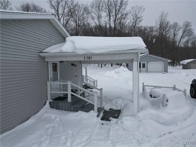 snow covered deck featuring a garage and an outdoor structure