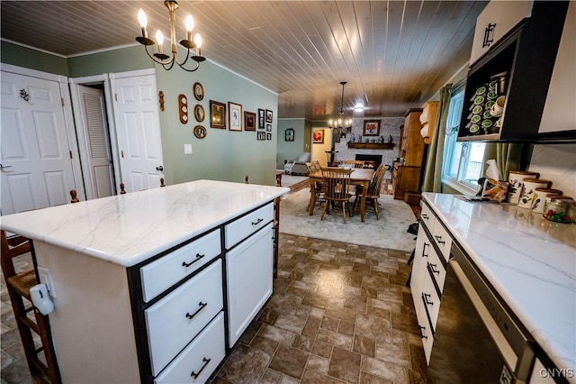 kitchen with pendant lighting, a center island, white cabinetry, a chandelier, and light stone counters