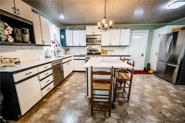 kitchen with a kitchen island, decorative backsplash, hanging light fixtures, stainless steel appliances, and white cabinets