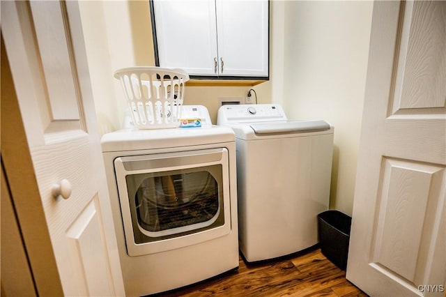 washroom with dark wood-type flooring, cabinets, and washer and dryer