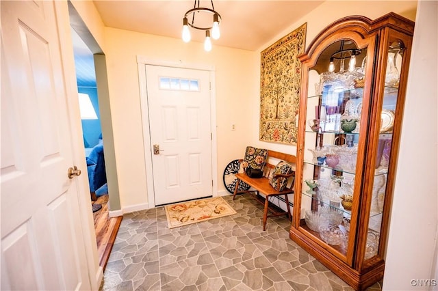 foyer featuring baseboards and stone finish floor