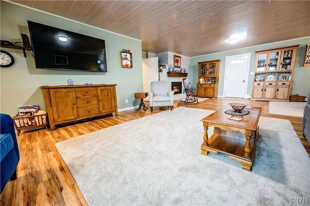 living room with light hardwood / wood-style floors, wood ceiling, and a fireplace