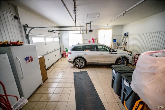 garage featuring white refrigerator and a garage door opener