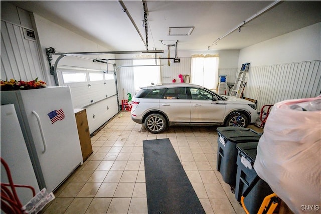 garage featuring freestanding refrigerator and a garage door opener
