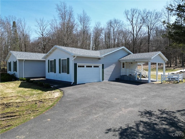 view of side of home with a carport, an attached garage, driveway, and roof with shingles