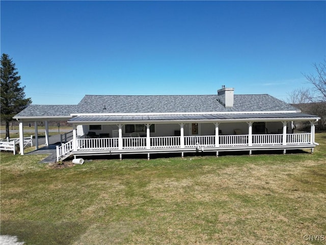 back of house with a shingled roof, a chimney, a lawn, and metal roof