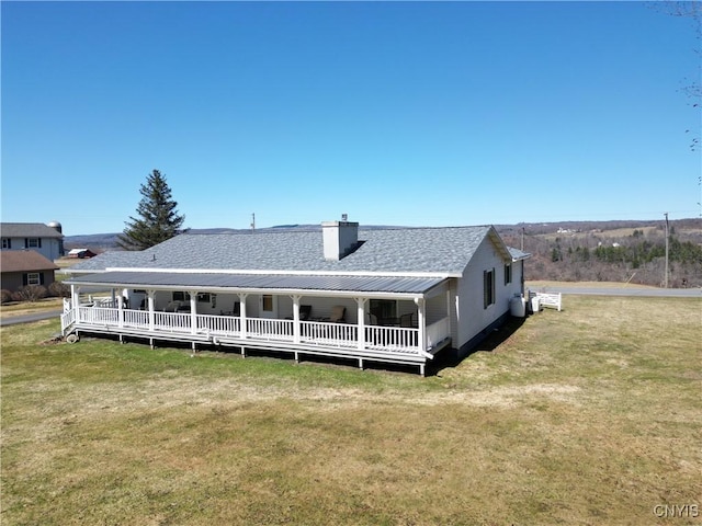 rear view of property with a yard, metal roof, and a chimney