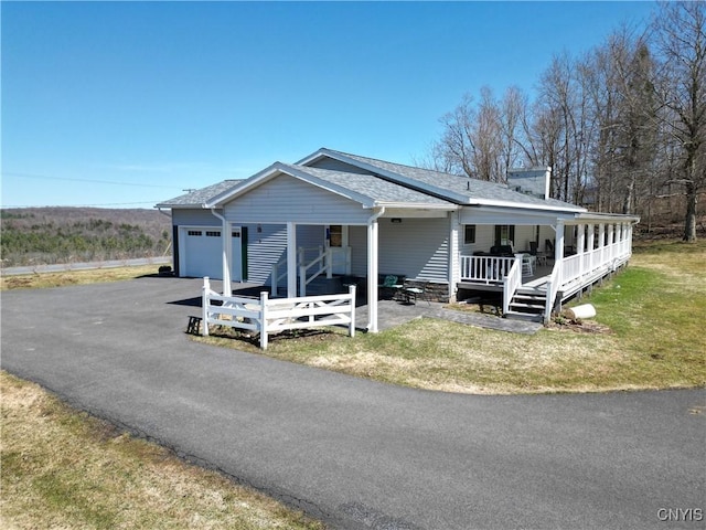 view of front of property featuring a shingled roof, a porch, a garage, a front lawn, and driveway