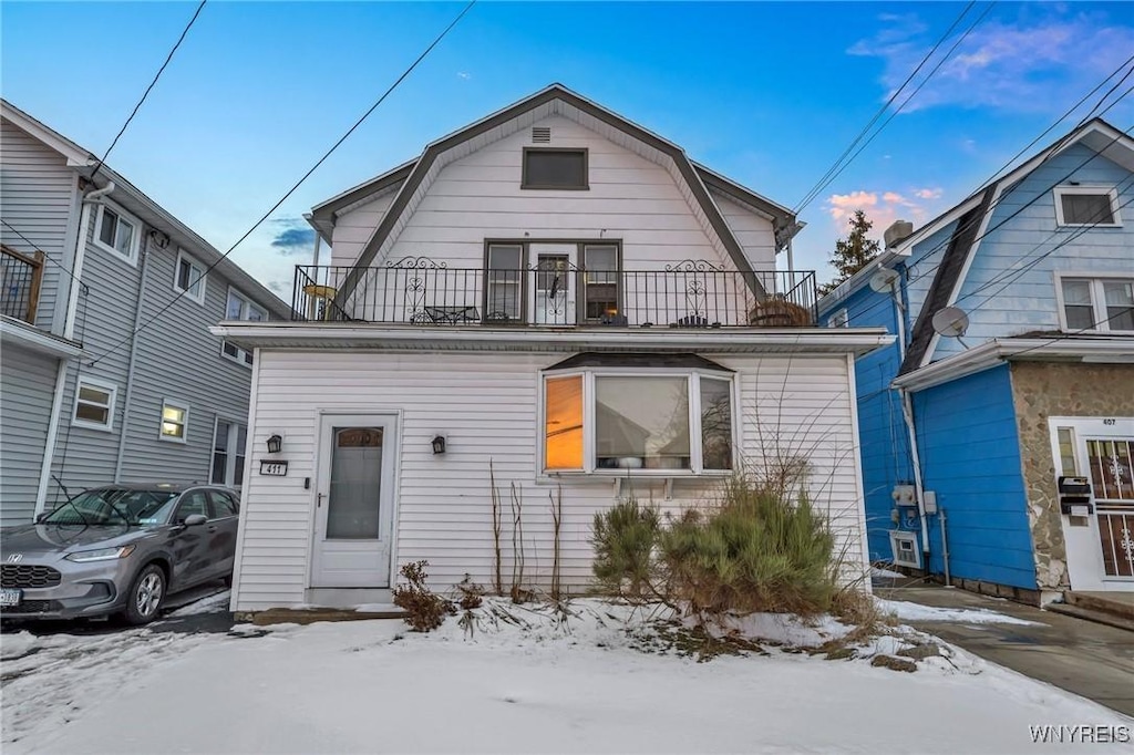 snow covered back of property with a balcony