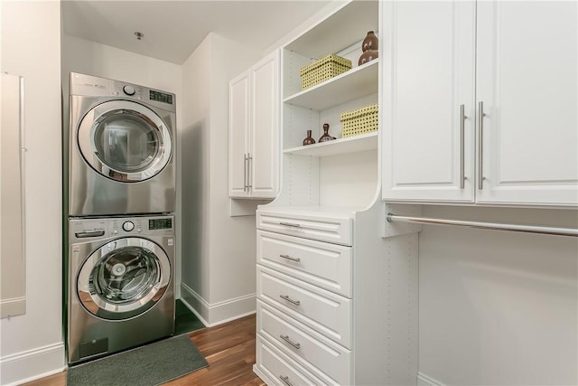 laundry room with stacked washer and dryer and dark hardwood / wood-style flooring