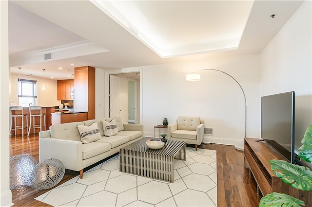 living room with light hardwood / wood-style floors and a raised ceiling