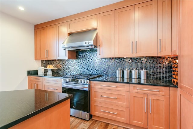 kitchen featuring tasteful backsplash, extractor fan, dark stone countertops, and stainless steel range with gas cooktop