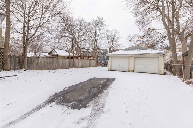 snowy yard featuring a garage and an outbuilding