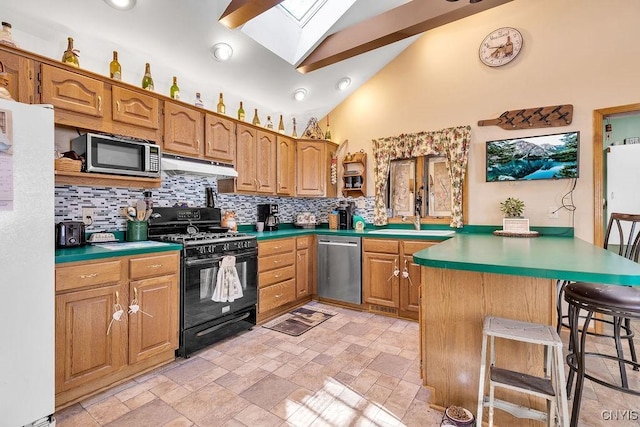 kitchen with vaulted ceiling with skylight, kitchen peninsula, sink, a breakfast bar area, and stainless steel appliances