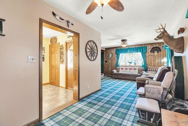 living room with ceiling fan, a textured ceiling, and wood walls