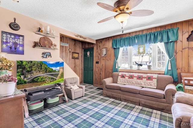 carpeted living room with ceiling fan, wood walls, and a textured ceiling