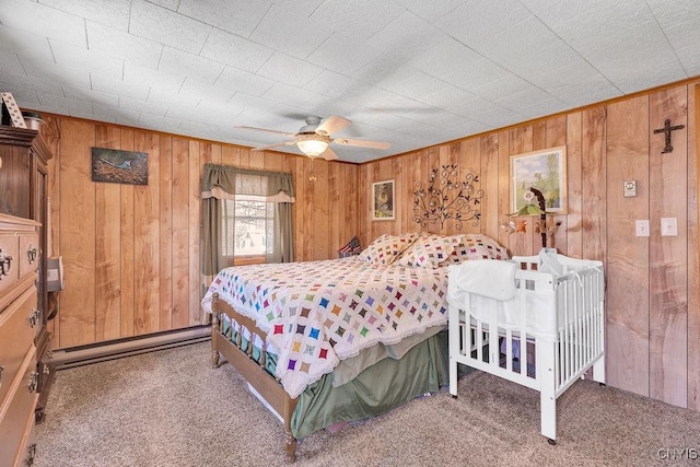 carpeted bedroom with ceiling fan, baseboard heating, and wood walls